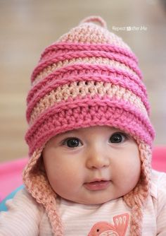 a baby wearing a crocheted hat sitting on top of a pink and blue plate