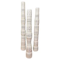 three tall white vases with designs on them are stacked up in the shape of poles