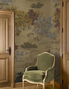 a green chair sitting in front of a wallpapered room with an open door