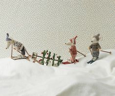 three toy mice are pulling a sleigh with christmas trees on it and snow