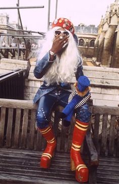 a man dressed as a pirate sitting on top of a wooden bench