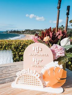 there is a vase with flowers in it on the table next to the ocean and beach