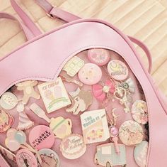 a pink heart shaped purse with lots of stickers on it