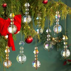 christmas ornaments hanging from a tree with red ribbon and lights on them, in front of a green background