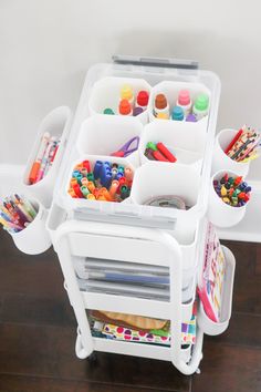 two plastic containers filled with lots of crafting supplies on top of a wooden floor