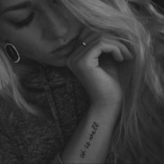 a woman with a tattoo on her arm looking down at her hand and the word love is written in cursive writing