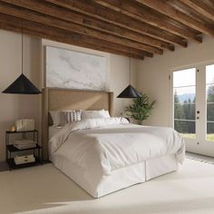 a large white bed sitting in a bedroom next to two windows