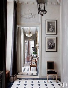 the hallway is decorated with black and white tiles, chandelier, and pictures on the wall