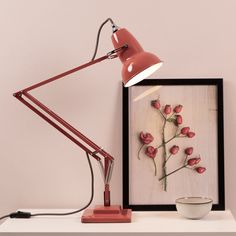 a red lamp sitting on top of a white shelf next to a framed photograph and bowl