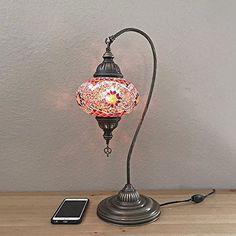 a lamp that is on top of a table next to a cell phone and charger