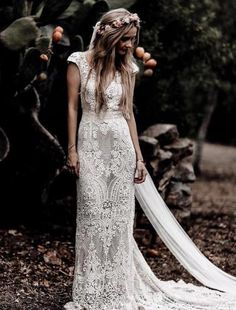 a woman in a wedding dress standing next to a tree and holding an apple with her hand