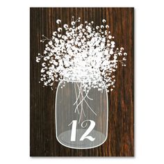 a mason jar filled with baby's breath flowers on top of a wooden table