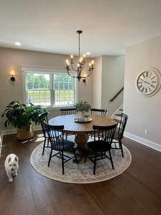 a dining room table with chairs and a dog standing in front of the table looking at it