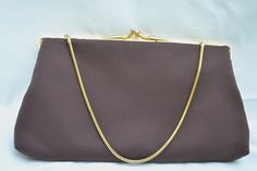 This elegant evening bag is simple and classic. The cloth material has a soft feel and the gold metal frame has a patterned design. The gold metal chain is a rounded slinky snake chain. The chain can be tucked inside so the bag can be used as a clutch. The lining is dark brown satin. Features one small pocket inside. Closure is a kiss lock clasp. Tag inside pocket is  'Styled by Du-Val Hand Made in Hong Kong'.  Measures 9 in. by 5 in. 1950's. Great condition. Classic Evening Pouch Bag, Classic Rectangular Evening Bag For Vintage Events, Chic Rectangular Bags For Vintage Events, Chic Rectangular Bag For Vintage Events, Brown Purse, Brown Satin, Brown Purses, Evening Purse, Purse Clutch