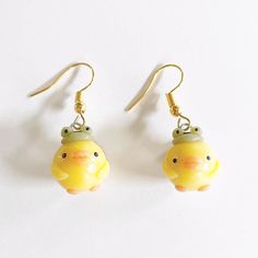 two small yellow fish shaped earrings on white surface with gold earwires and hooks