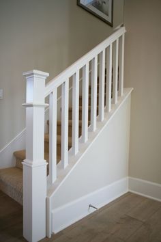 a white stair case next to a wooden floor