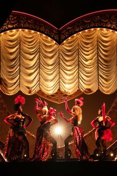 the dancers are performing on stage with their arms in the air and lights behind them