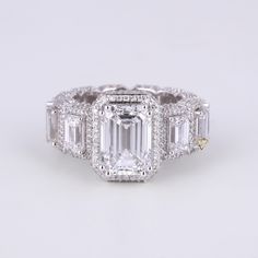 an emerald cut diamond ring with three baguetts on the sides and side stones