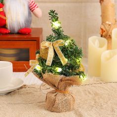 a small christmas tree in a burlap sack on a table next to a cup and saucer