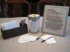 a table topped with cards, scissors and a jar filled with writing paper next to a sign