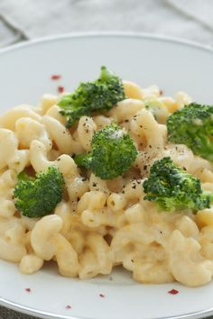 a white plate topped with macaroni and cheese covered in broccoli