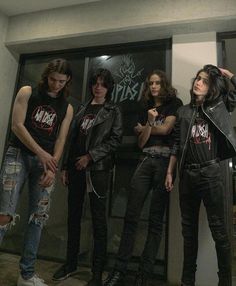 a group of young men standing next to each other in front of a wall with graffiti on it