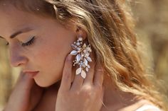 a woman with her hands on her face wearing earrings and holding her hand to her ear