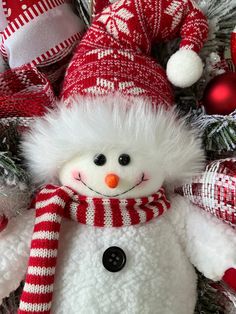 a snowman with a red and white striped scarf on it's head is surrounded by christmas decorations