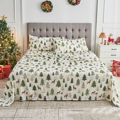 a bed with christmas trees and deers on it in front of two wreaths