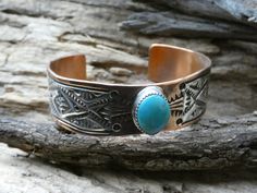 This is a beautiful Handcrafted Native American Navajo Made bracelet cuff. This is a wider cuff/bracelet about 3/4 inch width and is accented with a Turquoise Cabochon Gemstone. It is handcrafted with Copper and has a Hand Stamped Sterling Silver 925 designed Overlay.  There is also hand stamping on the copper part of the bracelet to give it a beautiful finished design. This Item is handcrafted here in the USA and is Hallmarked by the Artist. The cuff is entirely Handcrafted which makes it a ONE Southwestern Blue Cuff Bracelet As Gift, Western Style Bangle Jewelry Gift, Western Style Bangle Jewelry As Gift, Western Style Bangle As Gift, Stamped Turquoise Cuff Bracelet Gift, Artisan Cuff Bracelet With Concho As Gift, Turquoise Stamped Cuff Bracelet As Gift, Traditional Hand Tooled Turquoise Jewelry, Artisan Concho Cuff Bracelet As Gift