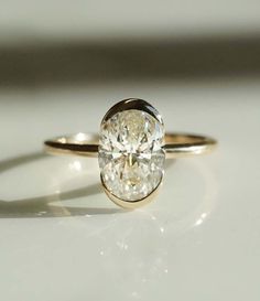 a close up of a diamond ring on a white surface with light shining through it