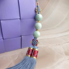 a tasseled necklace with beads and chains hanging from it on a purple surface