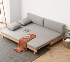 a living room with a couch bed and pillows on the floor next to a potted plant