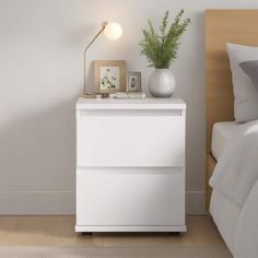 a white nightstand next to a bed in a bedroom