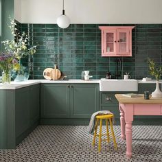 a kitchen with green tiles and pink accents