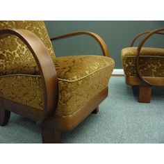 two wooden chairs sitting next to each other on a blue carpeted floor in front of a gray wall