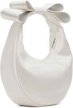 a white purse with a large bow on the front and side of it's handle