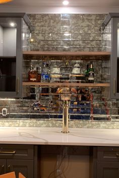 a kitchen counter with bottles and glasses on it's shelf above the bar area