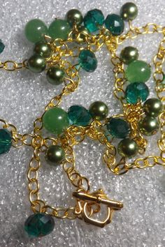 This necklace is 25 inches long, and has three shades of green beads. it has green jade beads, green crystal beads, and green pearl beads. This necklace is beaded on a gold tone chain with a gold tone tea pot toggle clasp. Elegant Green Beaded Chain Necklace, Green Beaded Chain Necklace As Gift, Gold Jade Beaded Necklaces With Gemstone Beads, Gold Beaded Jade Necklace, Gold Jade Beaded Necklaces With Gemstones, Gold Jade Gemstone Beaded Necklaces, Green Beaded Chain Necklace For Jewelry Making, Green Jade Beaded Chain Jewelry, Green Jade Jewelry With Beaded Chain