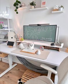 a white cat sitting on top of a desk next to a computer monitor and keyboard