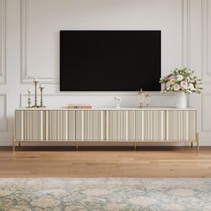 a large flat screen tv mounted to the side of a white wall next to a wooden floor