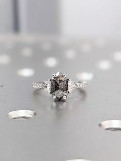 an engagement ring with a fancy diamond center surrounded by smaller diamonds on a shiny surface