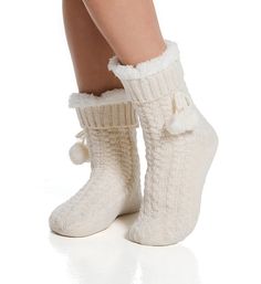 Slipper sock has fluffy sherpa (faux shearling) lining for a very cozy style. Soft cable knit has shimmery metallic threads. Pom-pom bow is sewn beneath cuff. Made of acrylic, polyester, metallic fibers. Sock has sherpa lining for extra softness and warmth. Ribbed knit cuff keeps sock in place. Decorative bow is sewn underneath cuff and has pom-pom detail. Metallic gold threads are woven into cable knit for shimmery look. Reinforced toe seam. Sole has anti-slip dots. Super cozy for cool weather. Soft Beige Winter Socks, Cozy Socks For Winter Loungewear, Cozy Socks For Loungewear In Winter, Warm Cozy Socks For Indoor Use, Cozy Warm Socks For Indoor Use, Snug Cozy Winter Socks, Cozy Warm Socks For Indoor, Warm Beige Socks For Winter, Cozy Snug Winter Socks