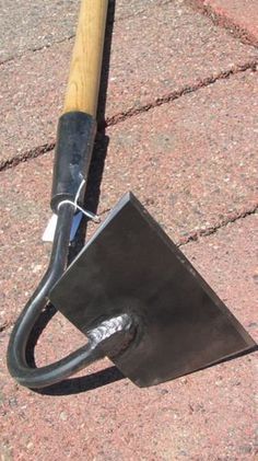 an upside down umbrella sitting on the ground next to a brick wall with a wooden handle