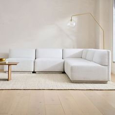 a white couch sitting on top of a wooden floor in a living room next to a table