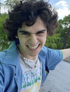 a man with curly hair is smiling and posing for the camera while holding his arm out