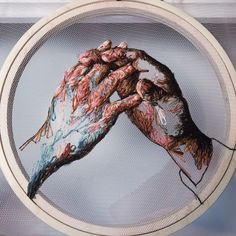 a painting of two hands holding each other on a white circular object in front of a window