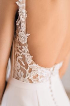 the back of a woman's wedding dress with white lace on top and bottom