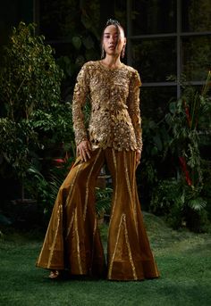 Discover elegance with this copper brown fitted straight top, handcrafted with intricate embellishments and cutwork embroidery. Adorned with beadwork, crystals, and sequins, it exudes a graceful luxe feel. Paired with straight pants that flare at the bottom and are adorned with hand embroidery for added sophistication. Glamorous Sets With Intricate Embroidery For Eid, Fitted Gold Palazzo Set With Intricate Embroidery, Glamorous Sharara With Resham Embroidery For Festive Occasions, Glamorous Festive Sharara With Resham Embroidery, Glamorous Festive Palazzo Set With Resham Embroidery, Evening Gold Hand-embellished Sets, Gold Hand Embellished Evening Sets, Gold Hand Embellished Sets For Evening, Gold Hand-embellished Evening Sets