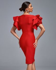 a woman wearing a red dress with ruffles on the sleeves and back, standing in